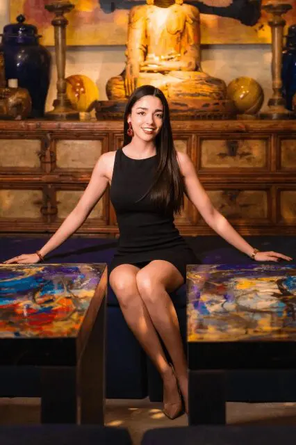 A woman sitting on top of a bed in front of a painting.